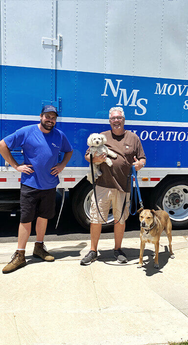 An NMS crew member with a customer and dogs beside an NMS truck